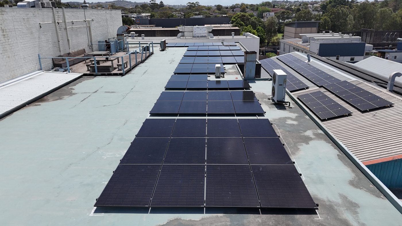 Aerial view of a commercial rooftop solar installation with dense rows of panels