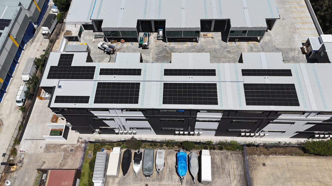 Aerial view of a large commercial rooftop solar installation across an industrial complex