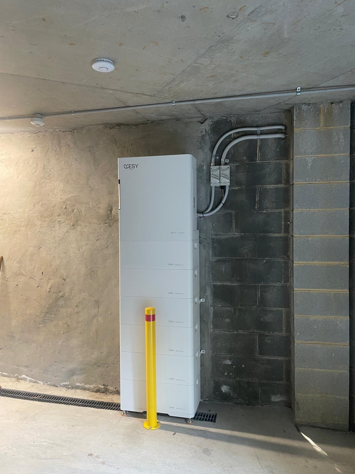 Installed ESY Sunhome HM10 battery stack in a basement car park, clearly branded with the ESY logo