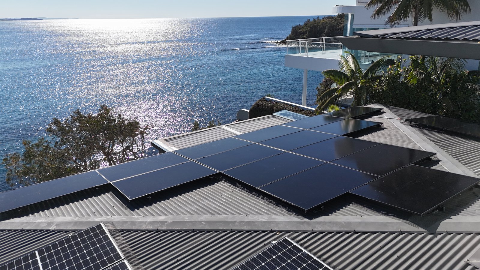 Close aerial view of a Manly rooftop solar install with ocean and cliffside views