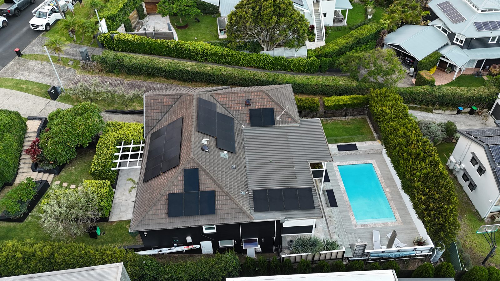 Aerial drone shot of a new rooftop solar installation on a tiled roof next to a swimming pool