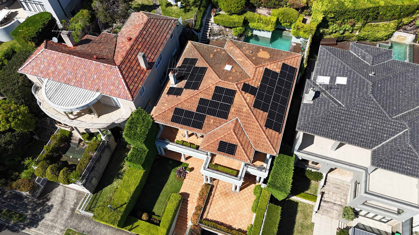 Aerial view of a large home surrounded by manicured hedges with solar panels