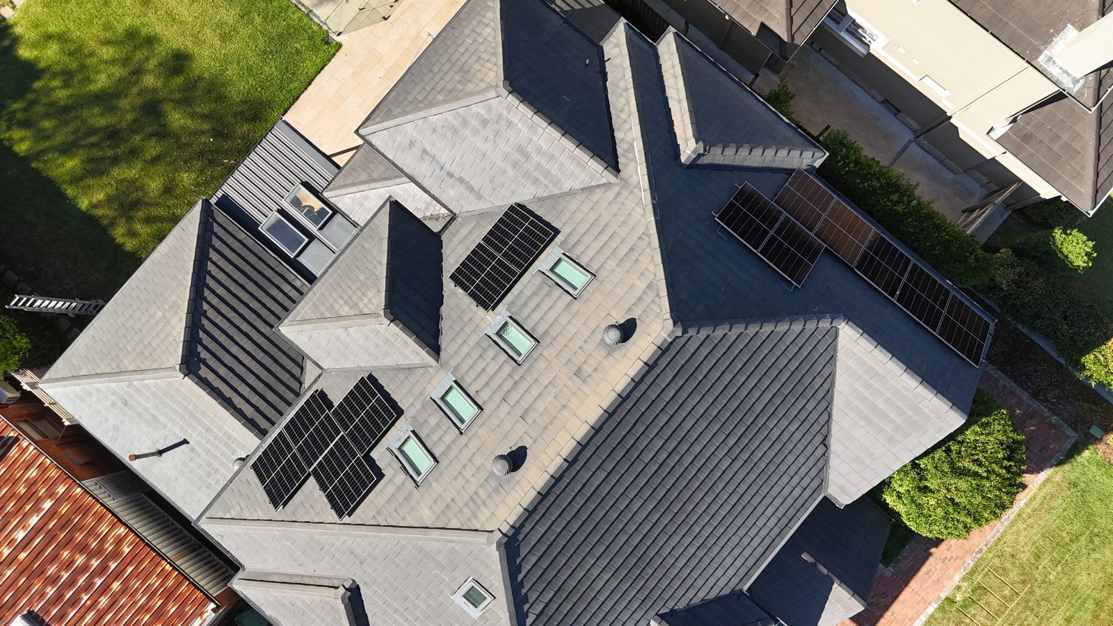 Aerial view of a modern black-roofed home with a full solar array installed