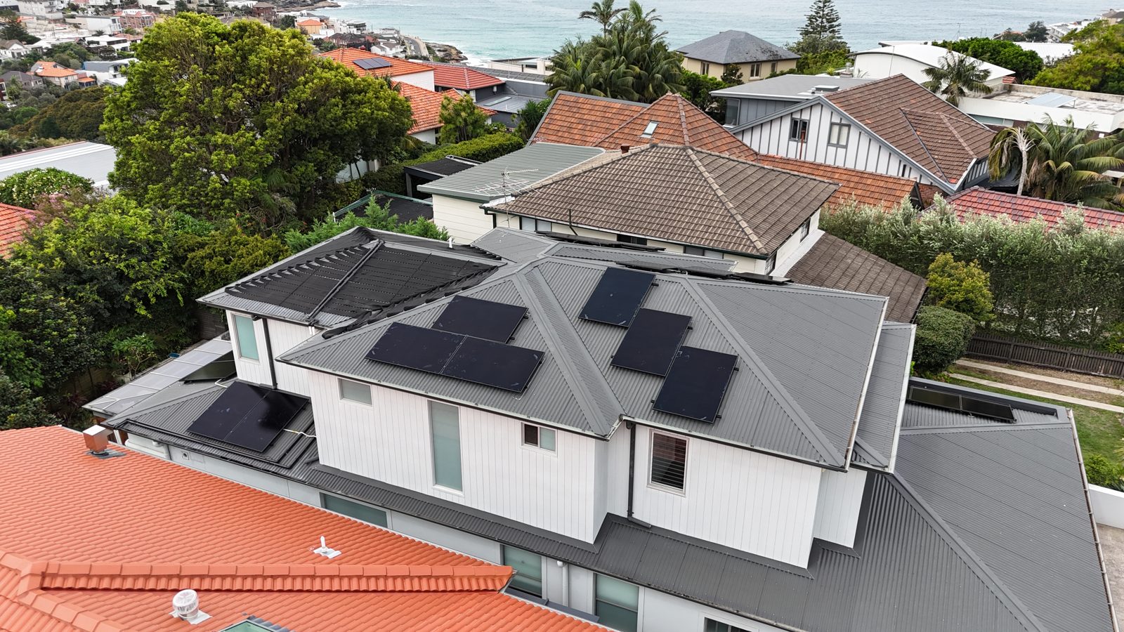 Aerial view of a sleek modern white building with a flat solar panel array
