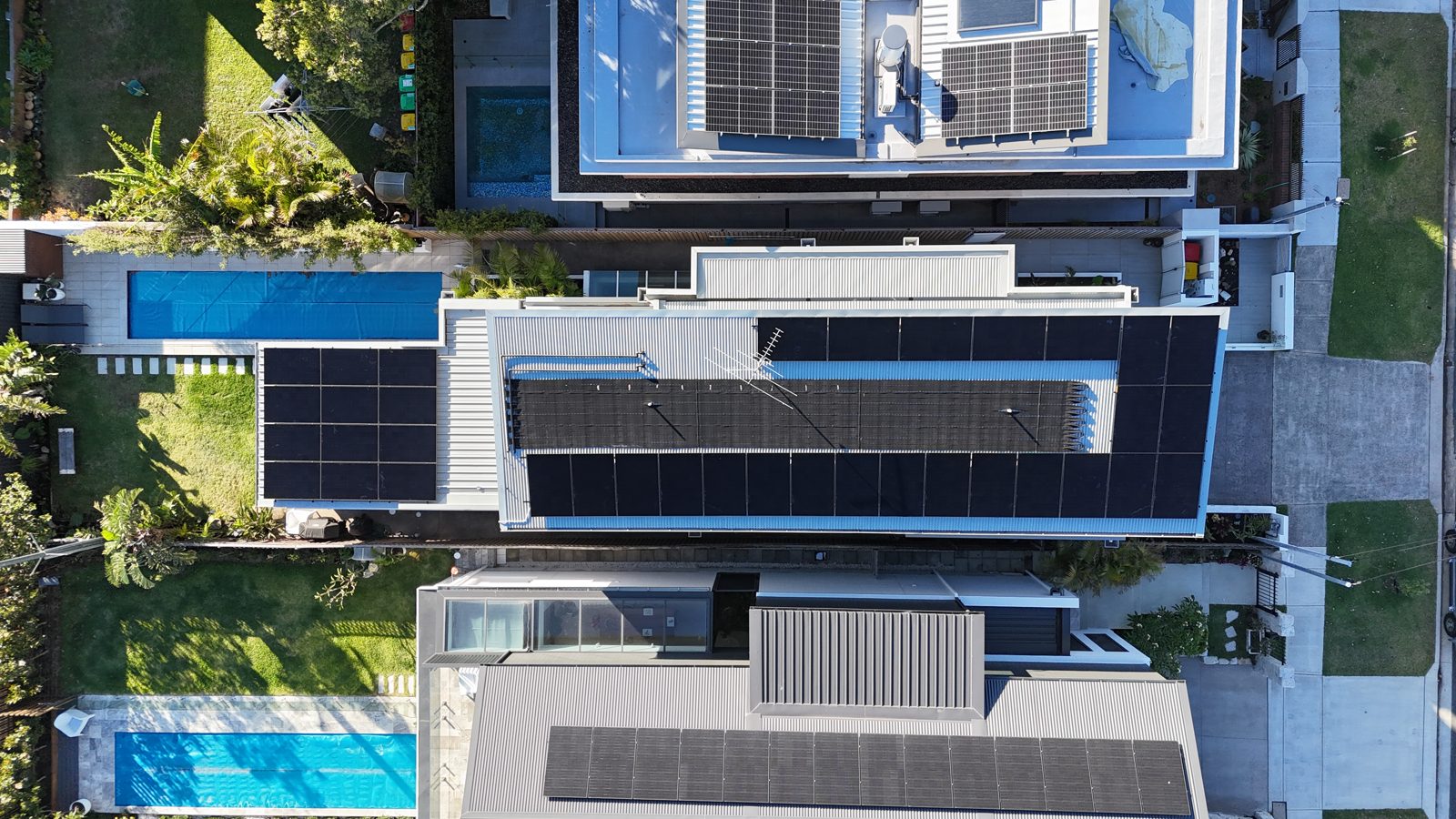 Aerial view of a large home with a pool and solar panels covering the roof