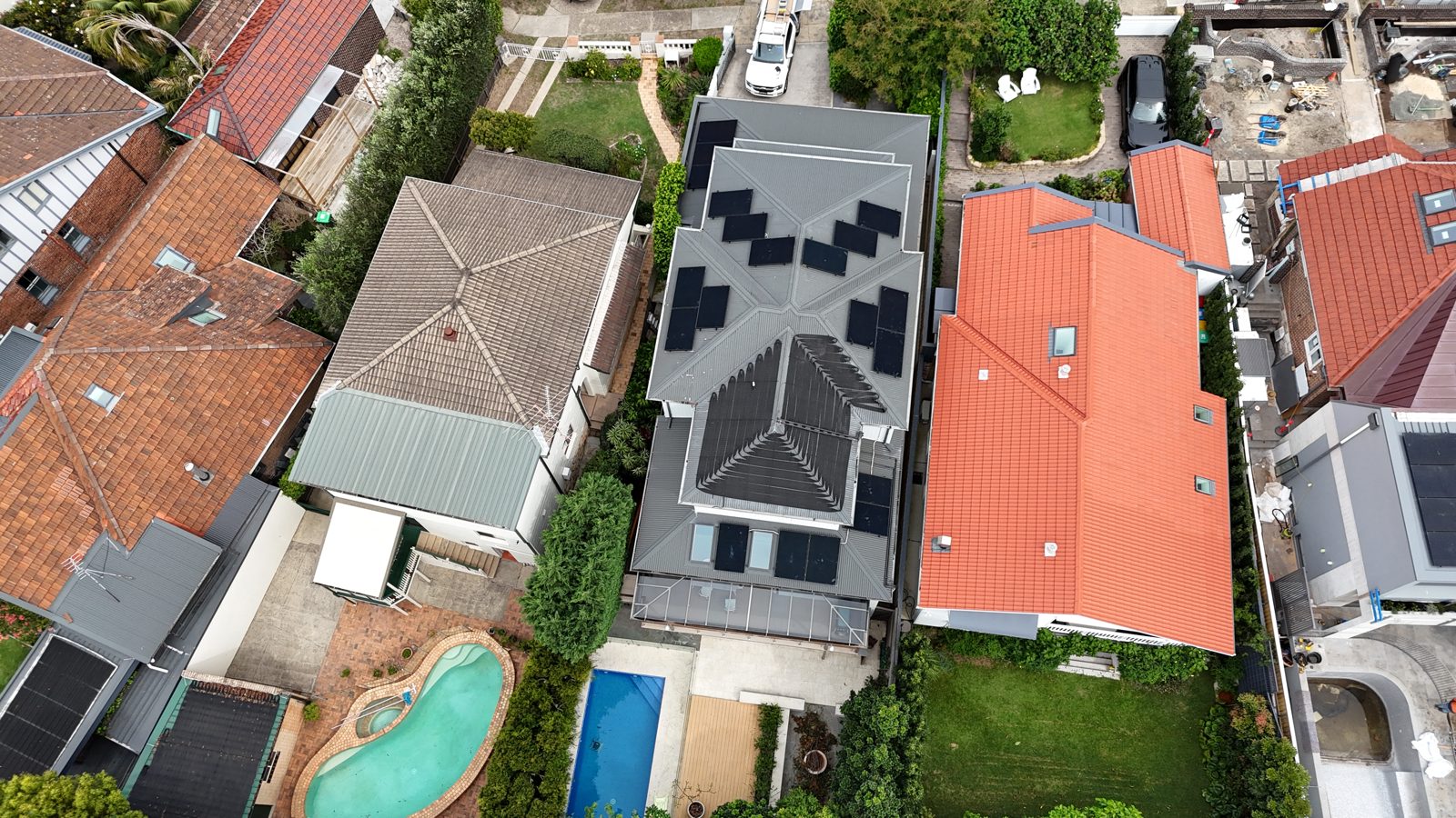 Aerial view of a home with a pool and terracotta roof, solar panels installed