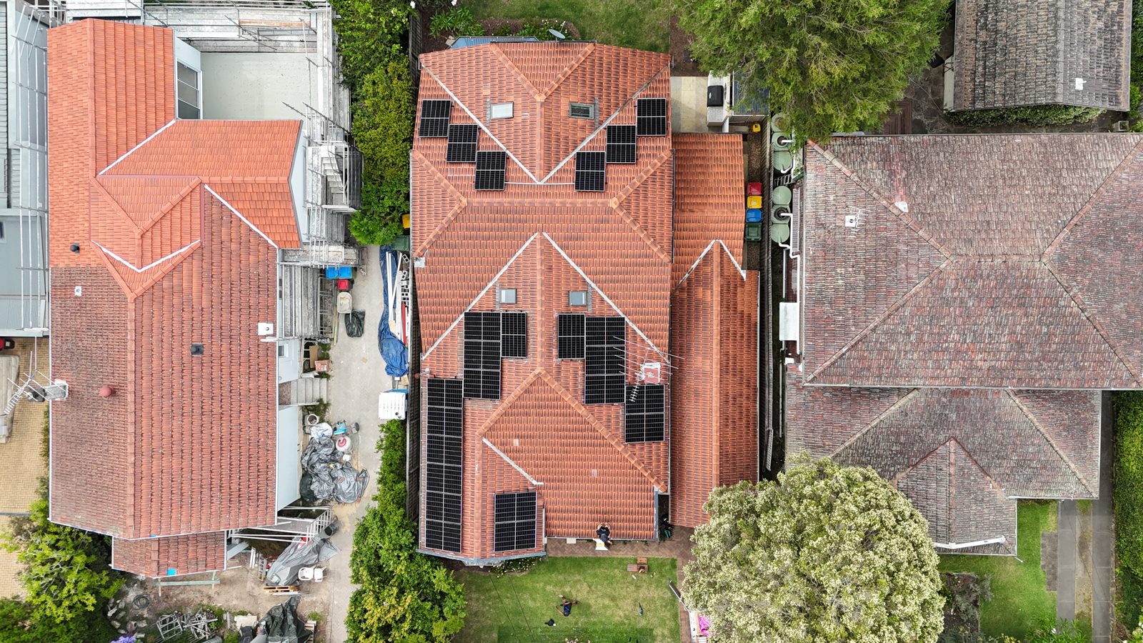 Aerial view of a terracotta tiled roof with a symmetrical solar panel layout