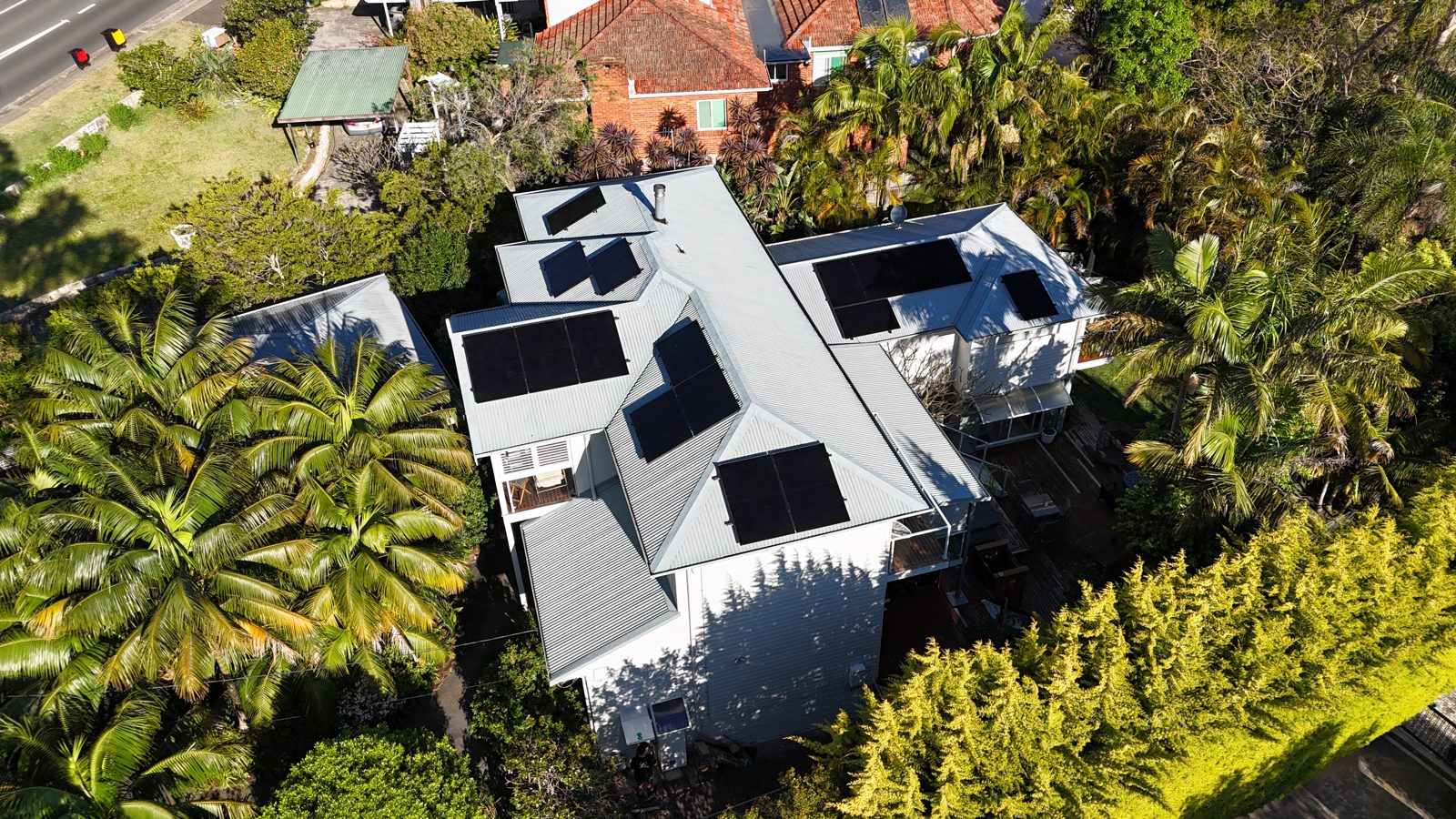 Aerial view of a modern home framed by tropical garden greenery with solar panels